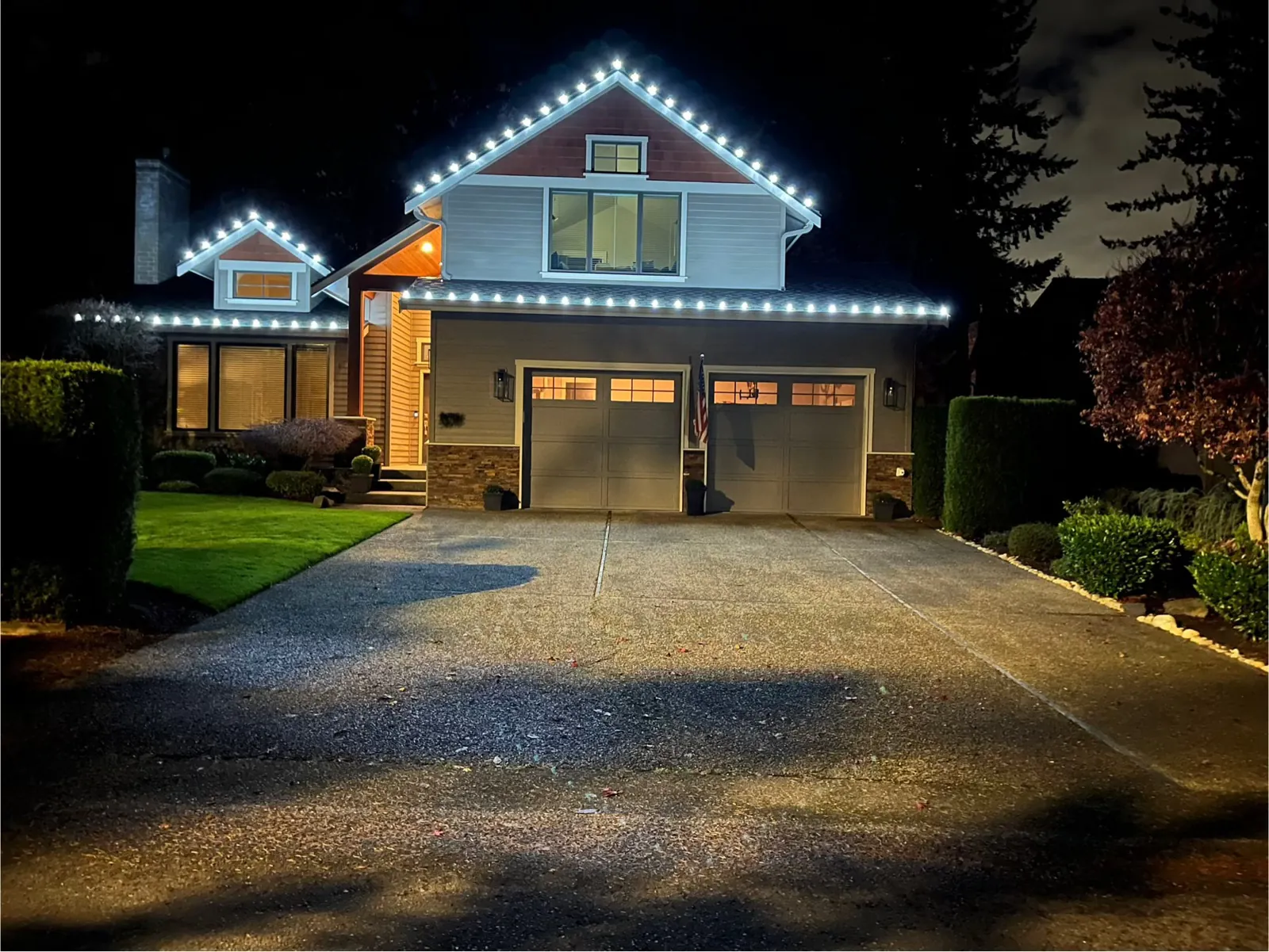 New England home with warm white Christmas lighting along the roofline